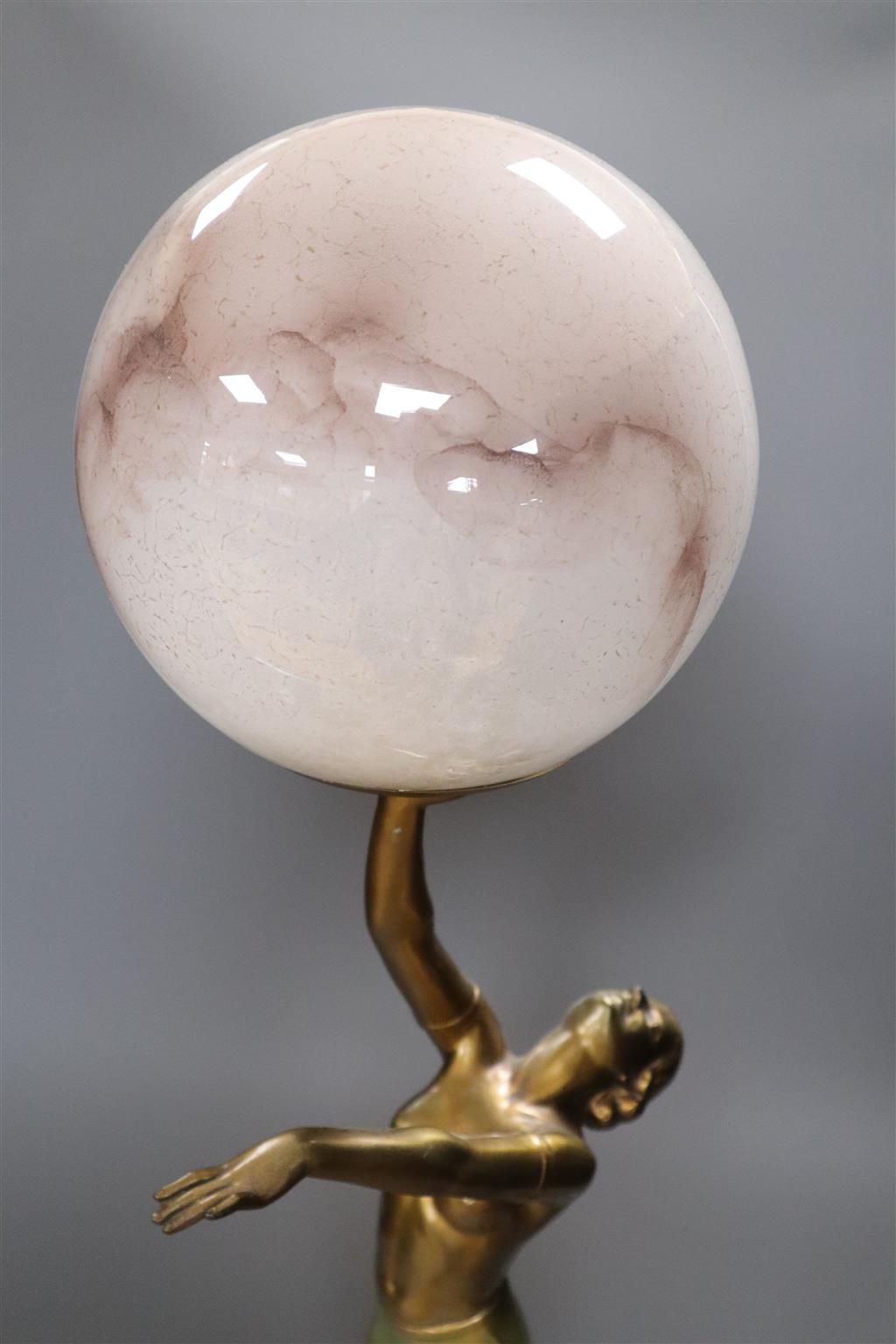 An Art Deco spelter figural table lamp, with semi-nude dancer holding a glass shade aloft, 64cm overall